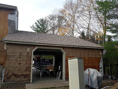 A partially constructed house with exposed plywood walls and a shingled roof.