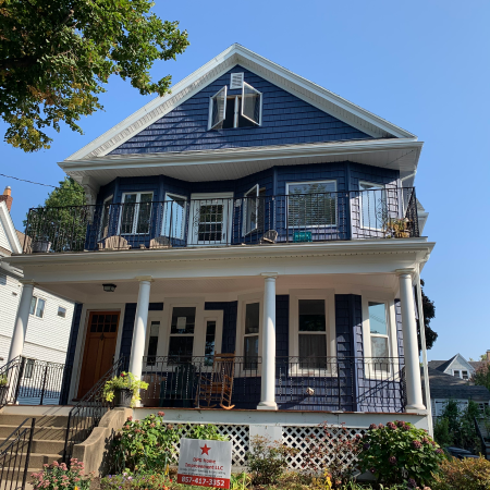 Two-story blue house with white trim, front porch, and balcony.