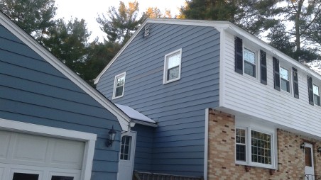 Blue and white two-story house with a brick base, black shutters, and a sloped roof.