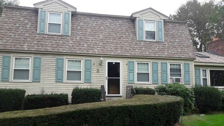 Two-story house with light blue shutters and grey siding.