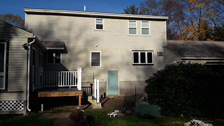 A beige two-story house with a small porch and steps on the left.