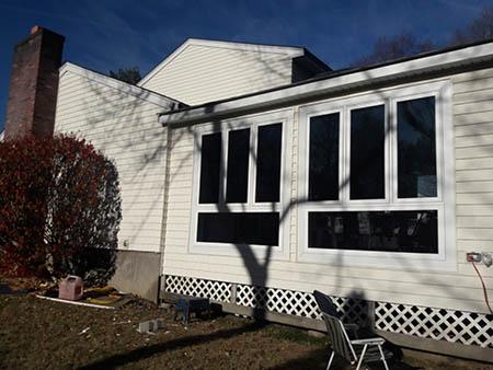 A beige house with large, black-framed windows and a chimney.